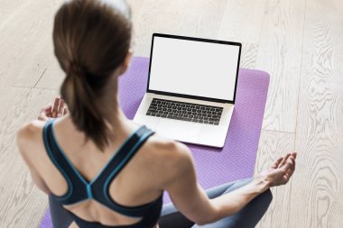 Evde yoga yapan genç bir kadın. Çevrimiçi video eğitimi. Egzersiz ve meditasyon yapan bir kız. Yoga, denge, meditasyon, rahatlama, sağlıklı yaşam tarzı, online eğitim konsepti. Boş monitör