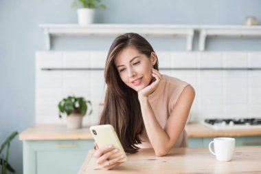 Okuyan ya da yemek tarifi arayan sevimli bir kadın. Öğrenci kız evde akıllı telefon kullanıyor. Bağlantı, iletişim, çevrimiçi alışveriş, uzaklık öğrenme, öğrenme, kilitleme kavramı