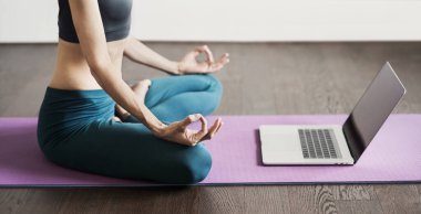 Evde yoga yapan genç bir kadın. Çevrimiçi video eğitimi. Egzersiz ve meditasyon yapan bir kız. Yoga, denge, meditasyon, rahatlama, sağlıklı yaşam tarzı, online eğitim sınıfı konsepti.