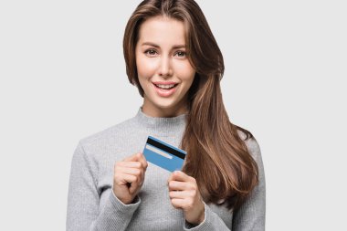 Beyaz arka planda kredi kartı tutan genç ve güzel bir kadın. Çevrimiçi alışveriş, e-ticaret, internet bankacılığı, para harcamak, hayattan zevk almak.