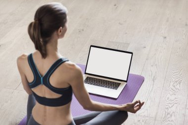 Evde yoga yapan genç bir kadın. Çevrimiçi video eğitimi. Egzersiz ve meditasyon yapan bir kız. Yoga, denge, meditasyon, rahatlama, sağlıklı yaşam tarzı, online eğitim konsepti. Boş monitör