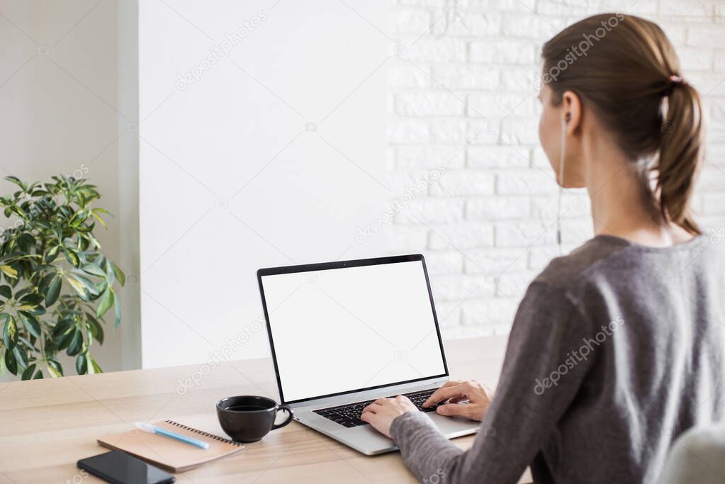 Young woman working at home. Student girl using laptop computer. Studying, freelance, online learning, distance education concept. Blank empty screen monitor