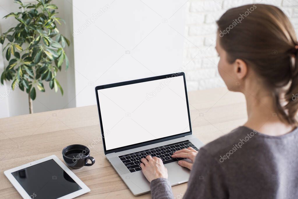 Young woman working at home. Student girl using laptop computer. Studying, freelance, online learning, distance education concept. Blank empty screen monitor