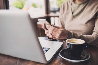 Kafede dizüstü bilgisayar ve akıllı telefon kullanan kadın. İş, teknoloji kavramı