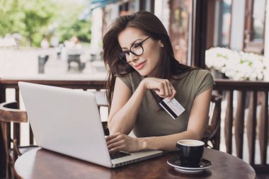 Kredi kartı tutan ve laptop kullanan bir kadın. İş kadını ya da girişimci çalışıyor. Çevrimiçi alışveriş, e-ticaret, internet bankacılığı, harcama, ev konseptinden çalışma