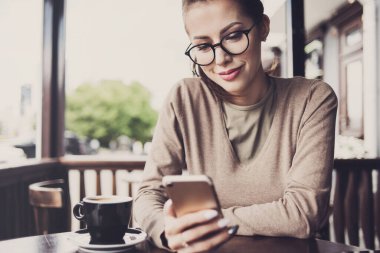 Kafede akıllı telefon kullanan güzel bir kadın. 