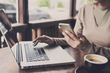 Kafede dizüstü bilgisayar ve akıllı telefon kullanan kadın. İş, teknoloji kavramı