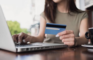 Kredi kartı tutan ve laptop kullanan bir kadın. İş kadını ya da girişimci çalışıyor. Çevrimiçi alışveriş, e-ticaret, internet bankacılığı, harcama, ev konseptinden çalışma