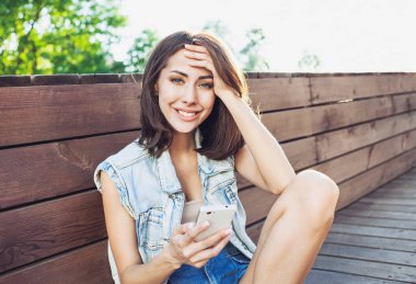 Genç kız açık havada akıllı telefon kullanıyor.