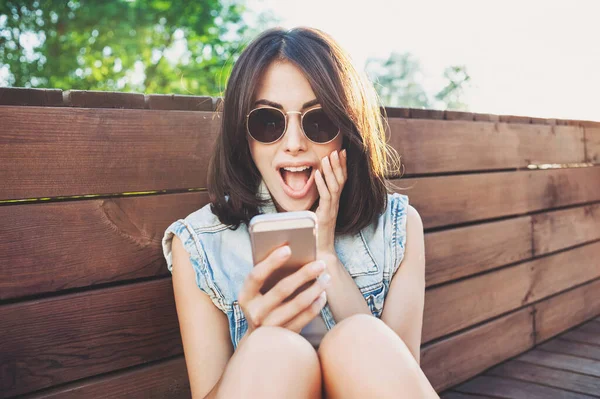 young girl in sunglasses using smart phone outdoors