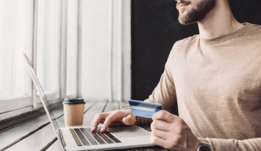 Dizüstü bilgisayar kullanan ve evde kredi kartı tutan bir adam. Ofiste çalışan genç bir iş adamı ya da girişimci. Çevrimiçi alışveriş, e-ticaret, İnternet bankacılığı, finans ve serbest konsept