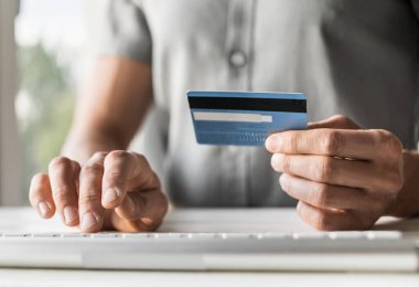 Adam bilgisayar kullanıyor ve kredi kartı tutuyor. Evde çalışan genç bir iş adamı ya da girişimci. Çevrimiçi alışveriş, e-ticaret, İnternet bankacılığı, finans ve serbest konsept