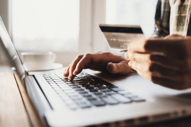 Dizüstü bilgisayar kullanan ve evde kredi kartı tutan bir adam. Ofiste çalışan genç bir iş adamı ya da girişimci. Çevrimiçi alışveriş, e-ticaret, İnternet bankacılığı, finans ve serbest konsept