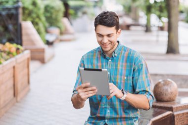 Bir şehirde dijital tablet kullanan bir iş adamı. Genç yakışıklı öğrenci kahve molası veriyor. Modern yaşam tarzı, bağlantı, eğitim, iş konsepti