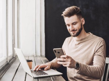 Bilgisayarda çalışan bir iş adamı. Ofiste akıllı telefon ve laptop kullanan bir adam. İnternet pazarlama, finans, iş konsepti