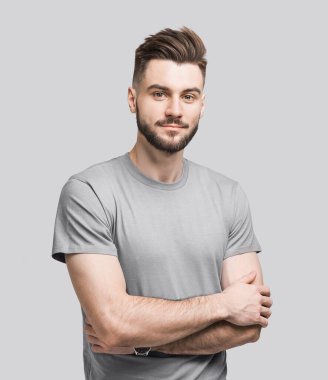 Portrait of handsome smiling young man with folded arms. Smiling joyful cheerful men with crossed hands studio shot. Isolated on gray background clipart