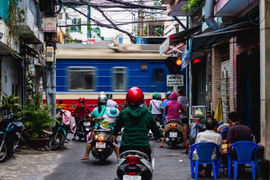 Ho Chi Minh, Vietnam - 19 Ocak 2017 Saigon sokaklarında renkli miğferli insanlar trenin geçmesini bekliyor..