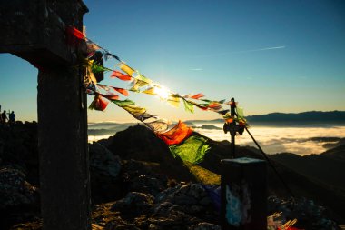 Güneşle şafak vakti dağın tepesinde renkli bayraklar