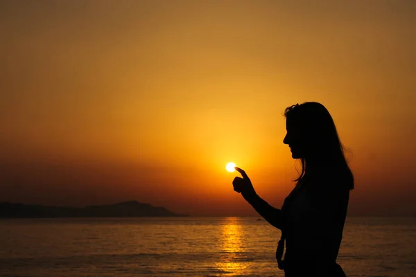 Gün batımındaki kız güneşe dokunuyor