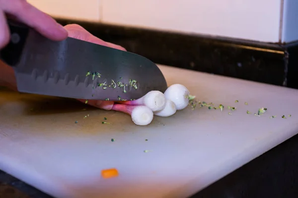 Mutfaktaki beyaz masada sebze kesen bıçaklı eller.