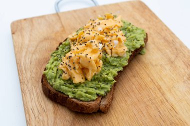 Tahtanın üstünde guacamole ve omlet ile tam buğday tostu.