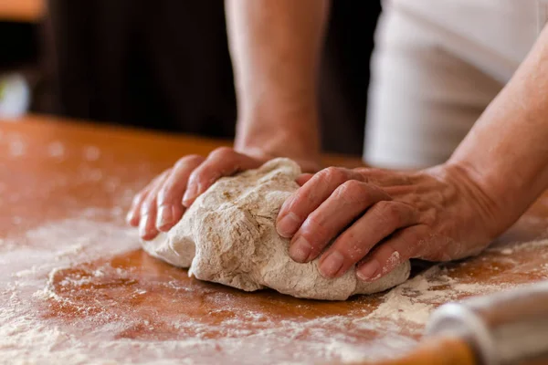 a person kneading the whole pizza dough