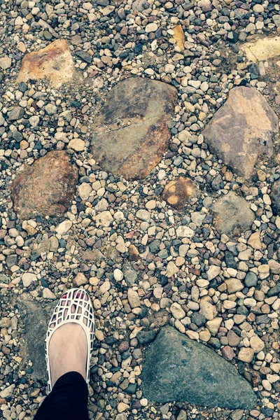 Kadın ayağı deniz taşlarının üzerinde duruyor..