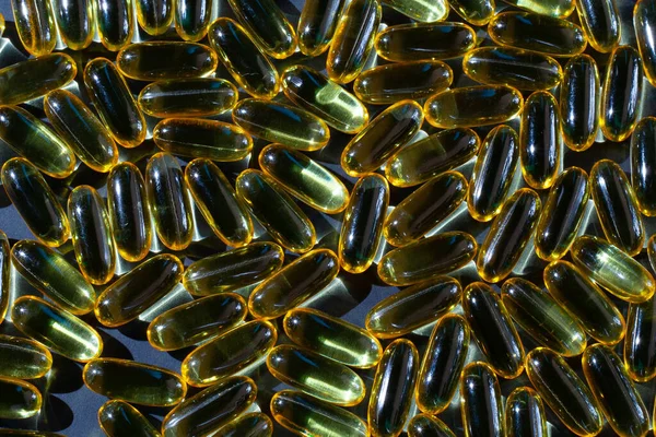 Omega-3 vitaminleri, yağ asitleri. Siyah arka planda sarı kapsüllerdeki balık yağı.
