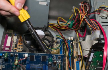 Bilgisayar mühendisi lehim demiriyle bir bilgisayarı tamir ediyor.