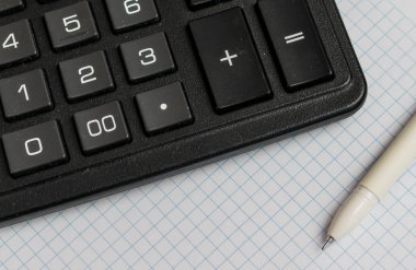 Kalem ve hesap makinesi masanın üzerinde.