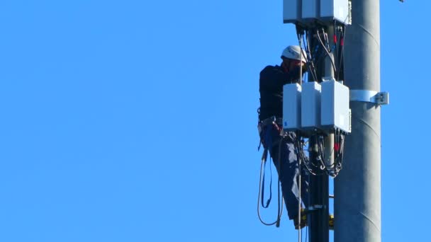 青い晴れた空の下で国内の携帯電話のアンテナで働く労働者は — ストック動画