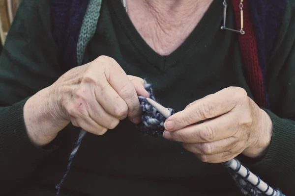 closeup on old lady hands to knitting in a terrace