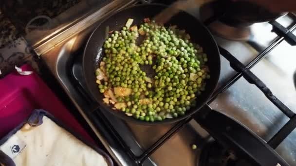 Pfanne Mit Zwiebelsauce Und Gefrorenen Erbsen Auf Dem Herd — Stockvideo