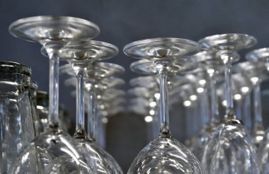 Sıraya dizilmiş bir sürü şarap kadehi, arka planda baş aşağı duran bir sürü şarap kadehi, koyu mavi arka planda baş aşağı duran. Cam çizgisi.