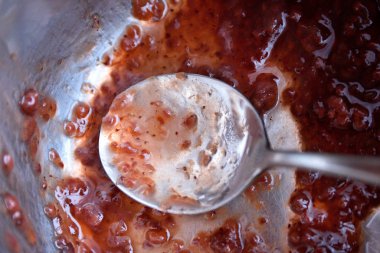 Paslanmaz çelik tencerede ahududu reçeli. Kaşıkla karıştırılmış. Kırmızı marmelat hazırlığı.