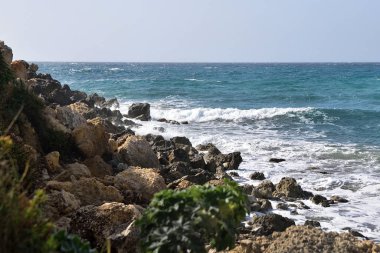Dalgalı deniz, deniz mavisi pastel rengi köpük, ufukta tuz sisi Malta Gghajn Tuffieha ve Golden Bay yakınlarında rüzgarlı açık hava. Tehlikeli kayalık sahil kayalıkları.