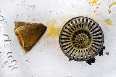 Kirli süzgeç paslanmaz çelik lavabo, balçık ve kirli atık, kötü mutfak hijyeni. Kullanılmış çay poşeti lavaboya atılmış..