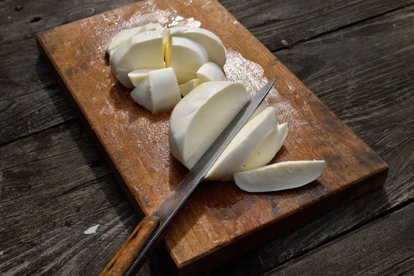 Dilimlenmiş mozarella, ahşap masa ve eski bıçak.