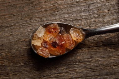 Tahta üzerinde kahverengi kehribar şekeri kristalleri olan kaşık..