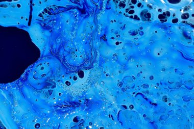 Mavi yüzey, farklı noktalar ve farklı renkler. Beyaz arka planda mavi boya, üst manzara. Soyut arkaplan.