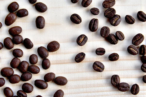 Coffee beans spilled on wooden desk, dark, brown, roasted. View from above.