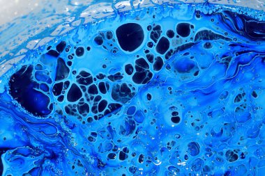 Mavi yüzey, farklı noktalar ve farklı renkler. Beyaz arka planda mavi boya, üst manzara. Soyut arkaplan.