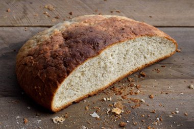 Kahverengi çıtır çıtır ekmekli ev yapımı ekmek, ikiye bölünmüş, ahşap masa kırıntıları..