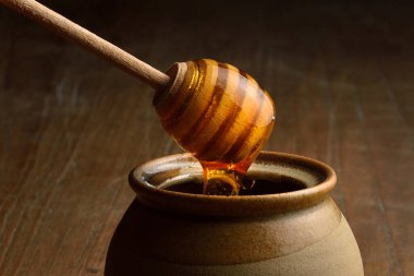 Bal, ahşap bal kaplamasından seramik bardağa dökülüyor. Tahta masadaki bal için toprak kapları..