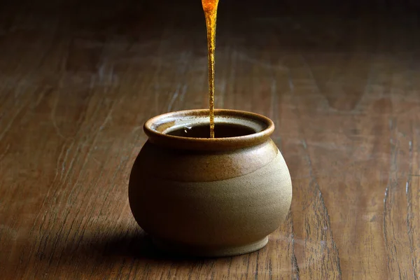 セラミックマグカップに蜂蜜を注ぐ 木製のテーブルの上に蜂蜜のための土器瓶 — ストック写真