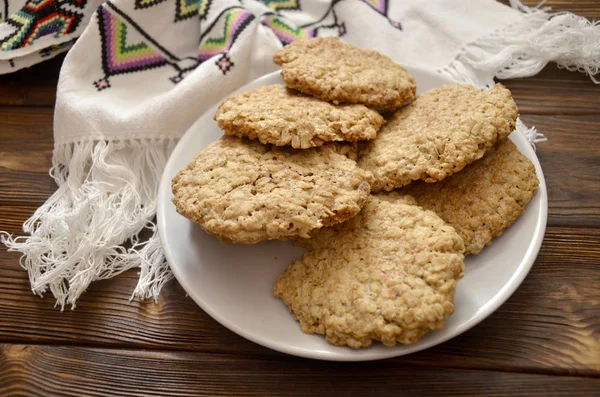 homemade oatmeal cookies on the table. Oatmeal cookies with splash of sunflower seeds, sesame seeds and raisin fresh from oven. Homemade oatmeal cookies folded in a pile on the old table