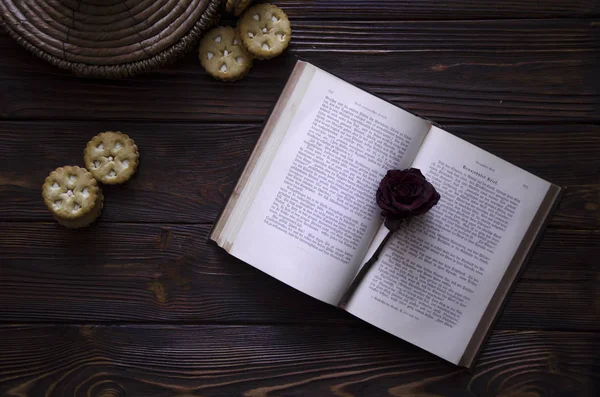En öppen bok med en röd ros blomma på den. Trä bakgrund. — Stockfoto