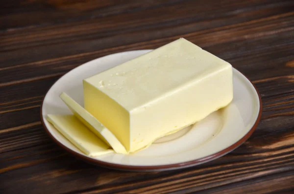 Tapis de beurre frais de ferme sur un plat de beurre avec un couteau à utiliser comme ingrédient à tartiner ou à cuire, vue aérienne sur une table à lattes en bois — Photo