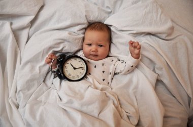 Yatakta yatarken bir çalar saat ile çocuk ve herkes iyi günler diler. iş zamanı. Uyku zamanı. En iyi viev