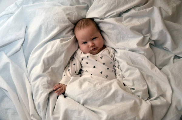 Child with an alarm clock lying on the bed, and wishes everyone a good morning. time to work. Time to sleep. Top viev — Stock Photo, Image